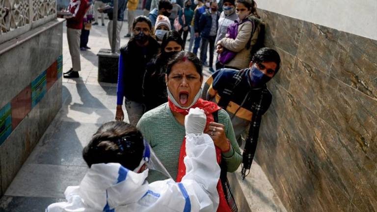 Un trabajador de la salud realiza una prueba de detección del coronavirus de las personas que hacen cola frente a una estación de metro en Nueva Delhi.