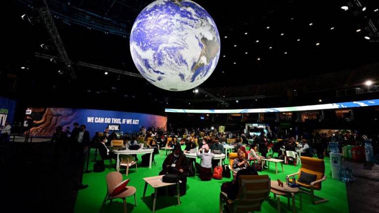Los delegados se sientan en la Zona de Acción mientras asisten al tercer día de la Cumbre del Clima de la ONU.