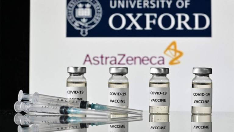 Una imagen muestra frascos con adhesivos de vacuna adheridos y jeringas, con el logotipo de la Universidad de Oxford y su compañía farmacéutica británica asociada AstraZeneca. Foto AFP