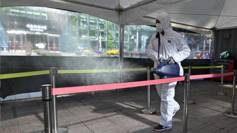Un trabajador de la salud rocía desinfectante durante un descanso en un centro de pruebas temporal para el coronavirus en Seúl.