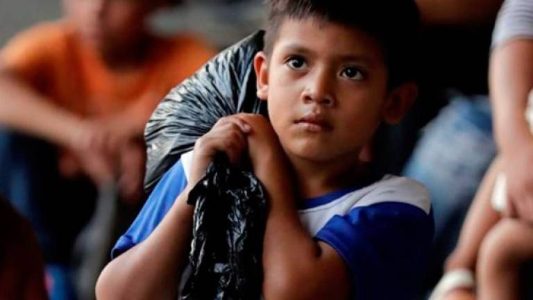 Un niño hondureño acompañado con su familiar (fuera de cuadro) carga una pequeña bolsa con ropa, en la Central de Transporte de la ciudad de San Pedro Sula al norte de Honduras.