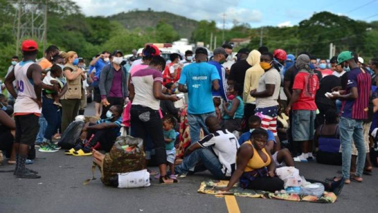 Miembros de una caravana de migrantes bloquean la carretera panamericana después de ser detenidos por la Policía Nacional. Foto AFP