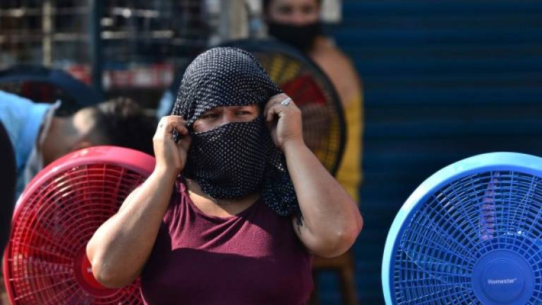 A woman covers her face against the spread of the new coronavirus at a market in Tegucigalpa on April 8, 2020. - 312 cases of COVID-19 were reported in Honduras, with 22 deaths. (Photo by ORLANDO SIERRA / AFP)