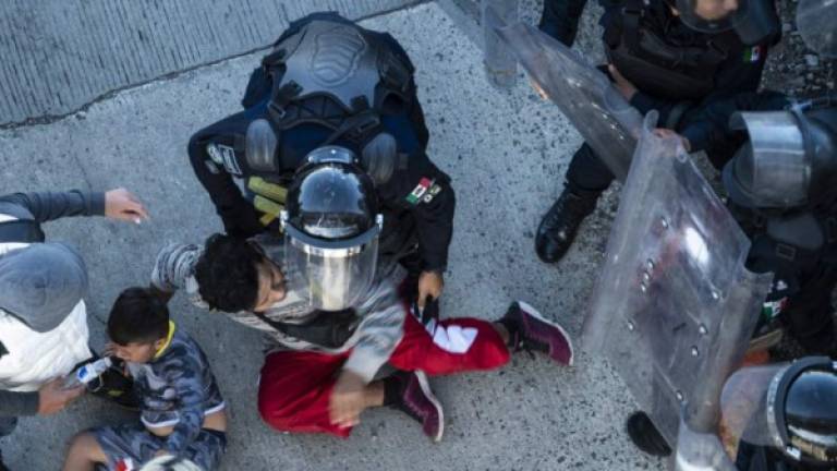 Central American migrants are stopped by Mexican police forces as they reach the El Chaparral border crossing, in Tijuana, Baja California State, Mexico, on November 25, 2018. - Hundreds of migrants attempted to storm a border fence separating Mexico from the US on Sunday amid mounting fears they will be kept in Mexico while their applications for a asylum are processed. An AFP photographer said the migrants broke away from a peaceful march at a border bridge and tried to climb over a metal border barrier in the attempt to enter the United States. (Photo by Pedro PARDO / AFP)