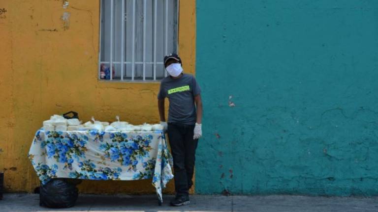 Un menor usando mascarilla vende lácteos en una calle de Tegucigalpa durante el toque de queda absoluto.