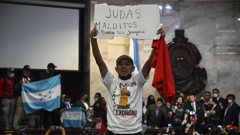 Un simpatizante del partido Libertad y Refundación (LIBRE) sostiene un cartel que dice “Maldito Judas, el pueblo te juzgará” al tomar posesión de la sede del Congreso de la República tras la elección de la Junta Directiva Provisional, en Tegucigalpa.