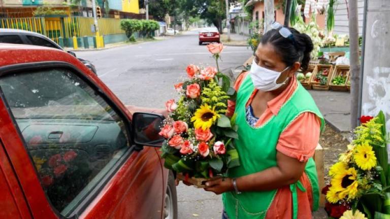 Suyapa Rodríguez ofrece un arreglo de rosas y girasoles a un posible cliente en el barrio Guamilito.Fotos: Gilberto Sierra.