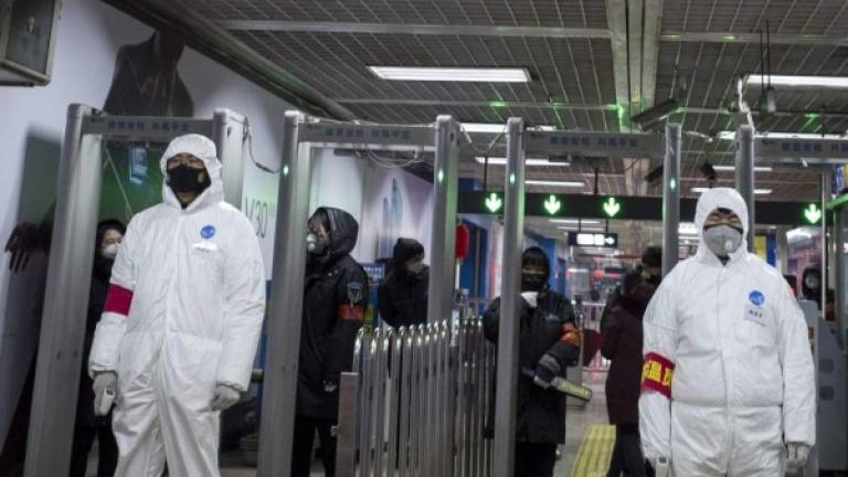 Security personnel wearing protective clothing to help stop the spread of a deadly virus which began in Wuhan, stand at a subway station in Beijing on January 26, 2020. - China on January 26 expanded drastic travel restrictions to contain a viral epidemic that has killed 56 people and infected nearly 2,000, as the United States, France and Japan prepared to evacuate their citizens from a quarantined city at the outbreak's epicentre. (Photo by NOEL CELIS / AFP)