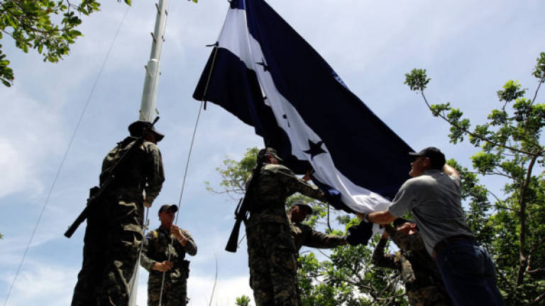 Militares hondureños izando la bandera de Honduras en la Isla Conejo. Foto de Archivo.