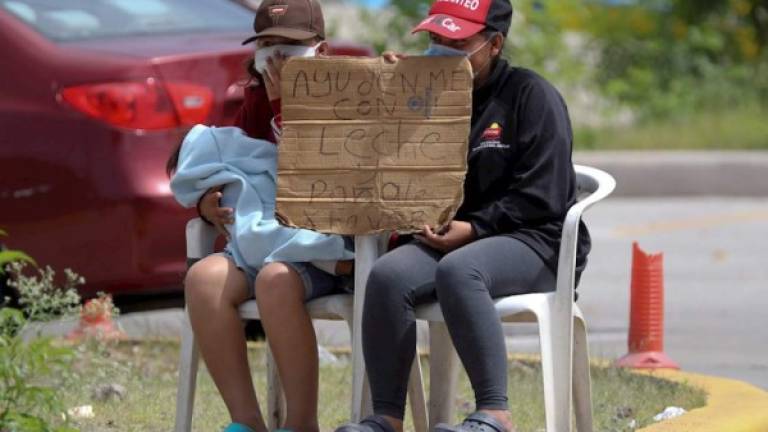 Dos mujeres piden dinero para alimentar a sus hijos este martes en Tegucigalpa.