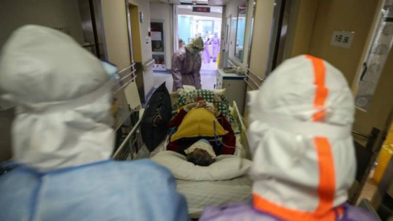 This photo taken on February 28, 2020 shows medical staff transferring a patient infected by the COVID-19 coronavirus at the Red Cross hospital in Wuhan in China's central Hubei province. - China on March 1 reported 35 more deaths from the new coronavirus, taking the toll in the country to 2,870. (Photo by STR / AFP) / China OUT