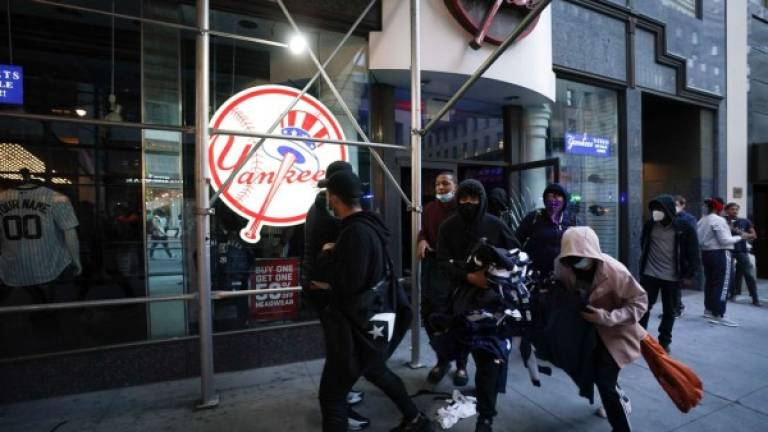 TOPSHOT - Protesters loot a NY Yankee store during demonstrations over the death of George Floyd by a Minneapolis police officer on June 1, 2020 in New York. - New York's mayor Bill de Blasio today declared a city curfew from 11:00 pm to 5:00 am, as sometimes violent anti-racism protests roil communities nationwide.Saying that 'we support peaceful protest,' De Blasio tweeted he had made the decision in consultation with the state's governor Andrew Cuomo, following the lead of many large US cities that instituted curfews in a bid to clamp down on violence and looting. (Photo by Bryan R. Smith / AFP)