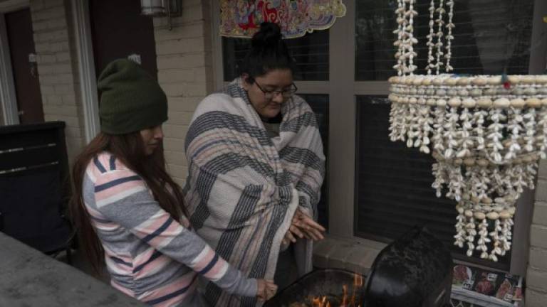 HOUSTON, TX - FEBRUARY 16: Karla Perez and Esperanza Gonzalez warm up by a barbecue grill during power outage caused by the winter storm on February 16, 2021 in Houston, Texas. Winter storm Uri has brought historic cold weather, power outages and traffic accidents to Texas as storms have swept across 26 states with a mix of freezing temperatures and precipitation. Go Nakamura/Getty Images/AFP== FOR NEWSPAPERS, INTERNET, TELCOS & TELEVISION USE ONLY ==