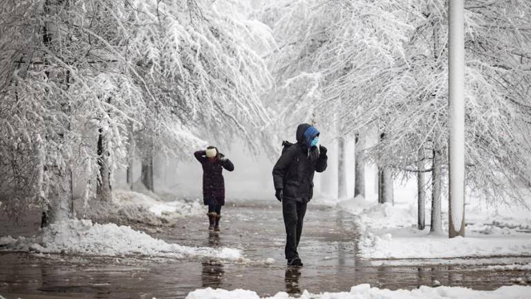 Peatones caminan por una acera nevada junto a la avenida Pennsylvania durante una tormenta de nieve en Washington, DC, Estados Unidos.