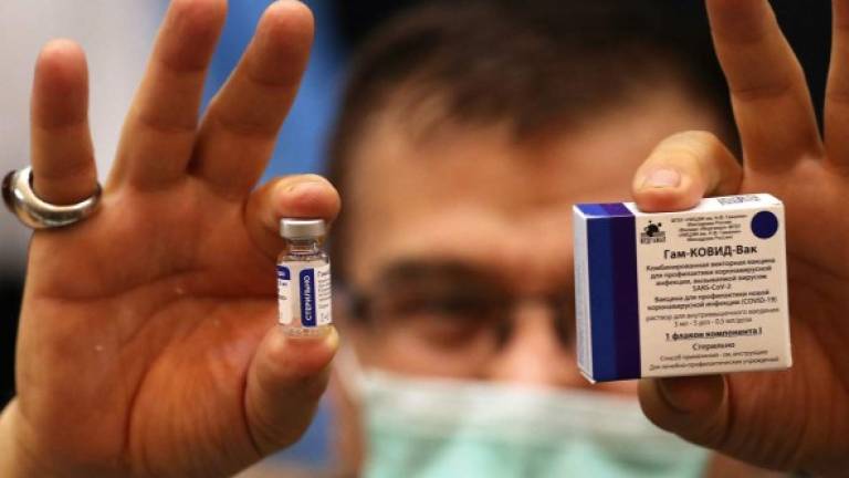 An Iranian health worker displays the Sputnik V coronavirus vaccine as the country launches its inoculation campain, at the Imam Khomeini hospital in the capital Tehran, on February, 9, 2021. - The inoculation effort for 80-million-plus population is starting with Russia's Sputnik V vaccine, authorities have said, as COVID-19 has infected 1.4 million people in Iran and killed more than 58,500, according to the health ministry. (Photo by ATTA KENARE / AFP)
