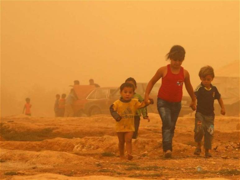 Niños sirios caminando durante la tormenta de arena.