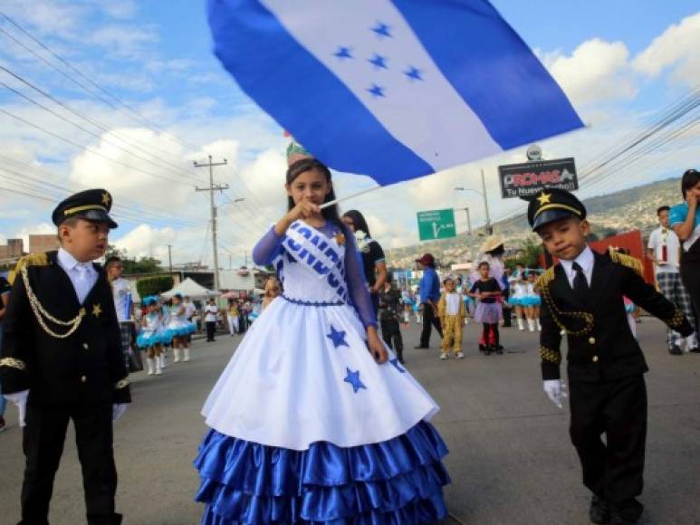 En la imagen, dos menores disfrazados de cadetes acompañan a una niña cuyo traje es la representación de la bandera nacional.