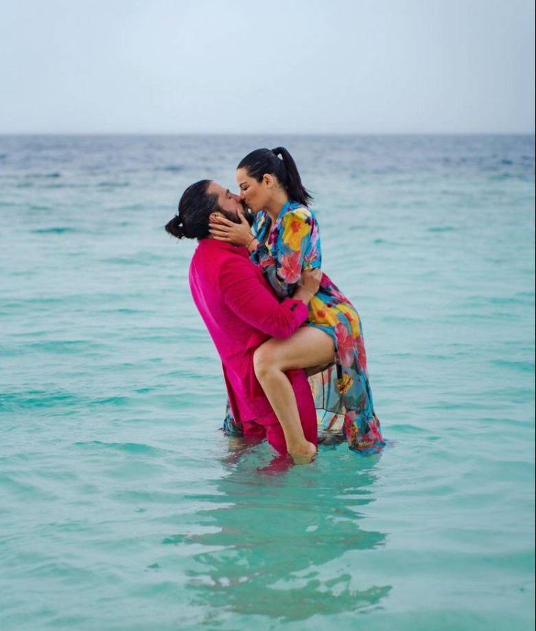 En las fotos se puede observar a Maite Perroni luciendo un vestido floreado y a su esposo Andrés portando un traje en color rosa, combinado con una playera blanca, todo esto mientras pasean por una soleada playa y un mar completamente azul. 