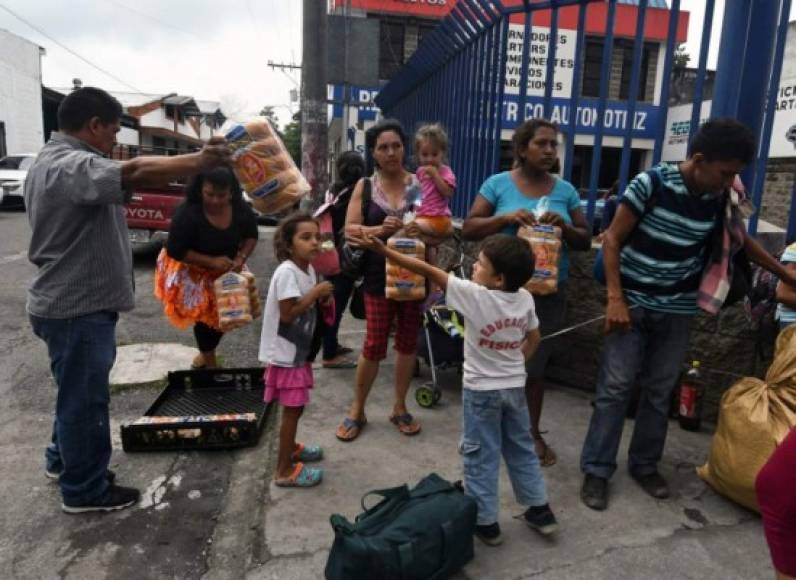A Guatemalan offers bread bags to Honduran migrants taking part in a caravan towards the United States, as they arrive in Guatemala City, on October 17, 2018. - A migrant caravan set out on October 13 from the impoverished, violence-plagued country and was headed north on the long journey through Guatemala and Mexico to the US border. President Donald Trump warned Honduras he will cut millions of dollars in aid if the group of about 2,000 migrants is allowed to reach the United States. (Photo by ORLANDO SIERRA / AFP)