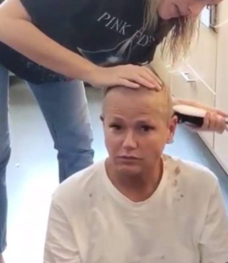 Sasha Meneghel Szafir le cortó el pelo en el piso de una cocina con una cortadora de mano.