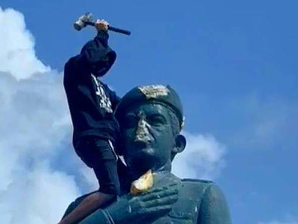 Venezolano encima de la estatua de Hugo Chávez.