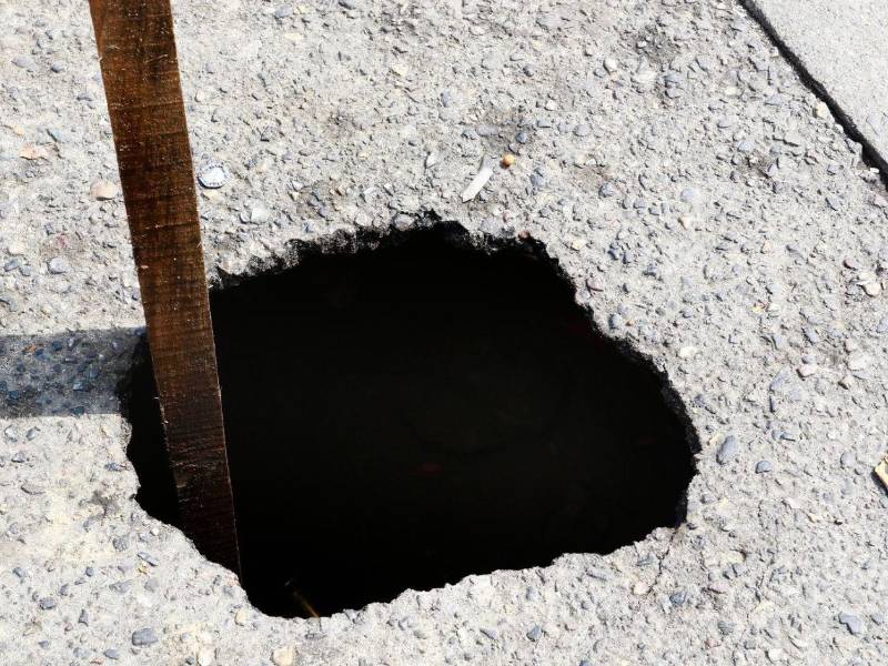 Los comerciantes pusieron una tabla de madera en el agujero para alertar a los que van en carro, motos o a pie.