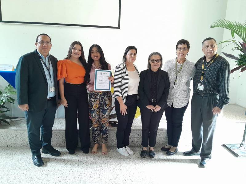 Luis Cruz, la doctora Mirta Ruano, la científica Mary Lorena Vallecillo, Patricia Murillo y René Gavarrete, entregan reconocimiento a dos estudiantes de Periodismo, ganadoras del primer lugar en la categoría Poster.