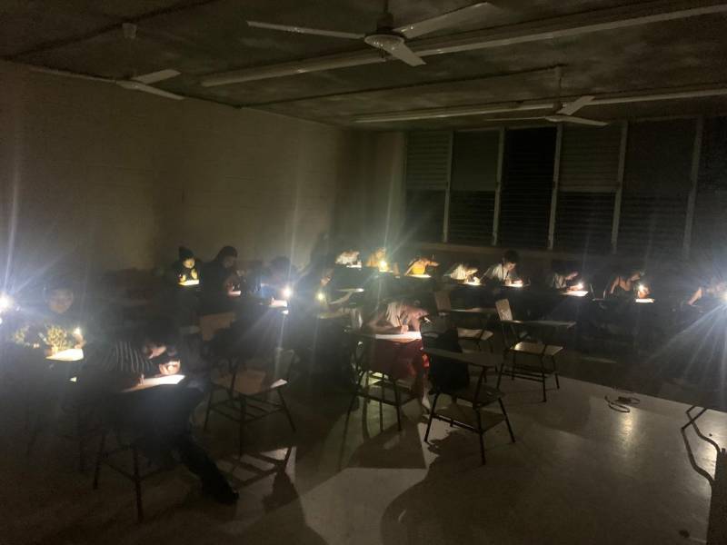 Estudiantes de la clase de Géneros Periodísticos en Unah-vs, realizan su examen con la luz de sus celulares.