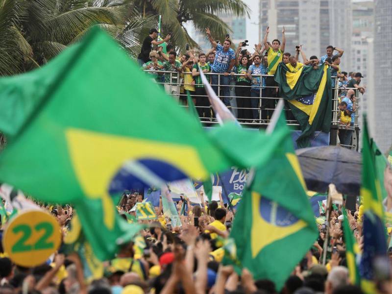 El candidato a la Presidencia de Brasil, Flávio Bolsonaro (c), saluda a sus simpatizantes durante un acto de campaña este sábado, en la playa de Barra da Tijuca, en Río de Janeiro (Brasil).
