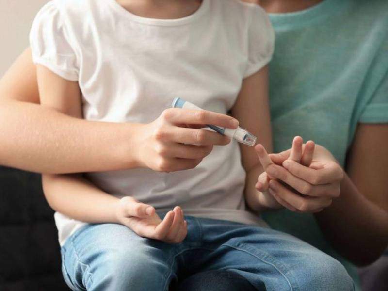 Una madre toma una muestra de sangre a su hija diagnosticada con diabetes en una fotografía de referencia.