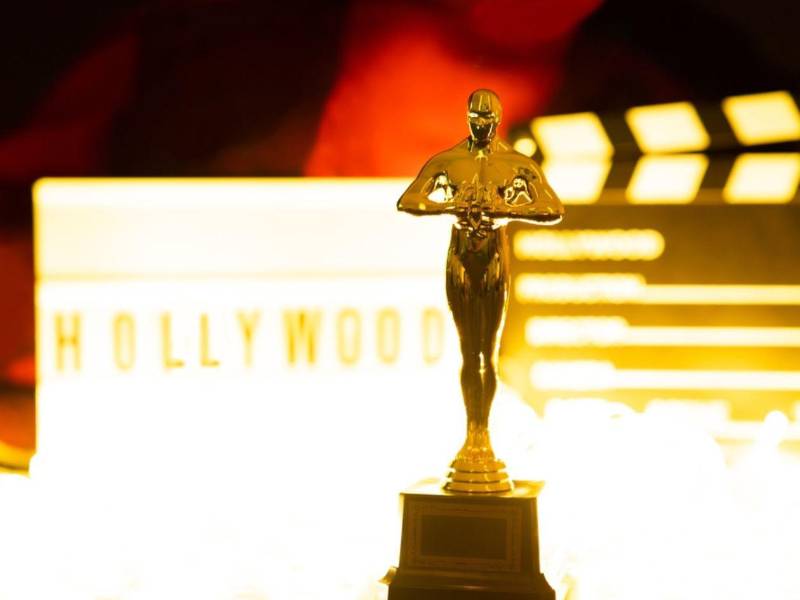Un premio Oscar con un fondo en el que se muestra una claqueta y un rótulo con la leyenda Hollywood. Imagen de referencia.