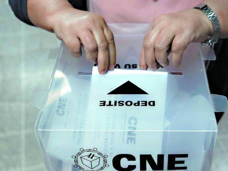 Mujer deposita su voto en una urna | Fotografía de archivo