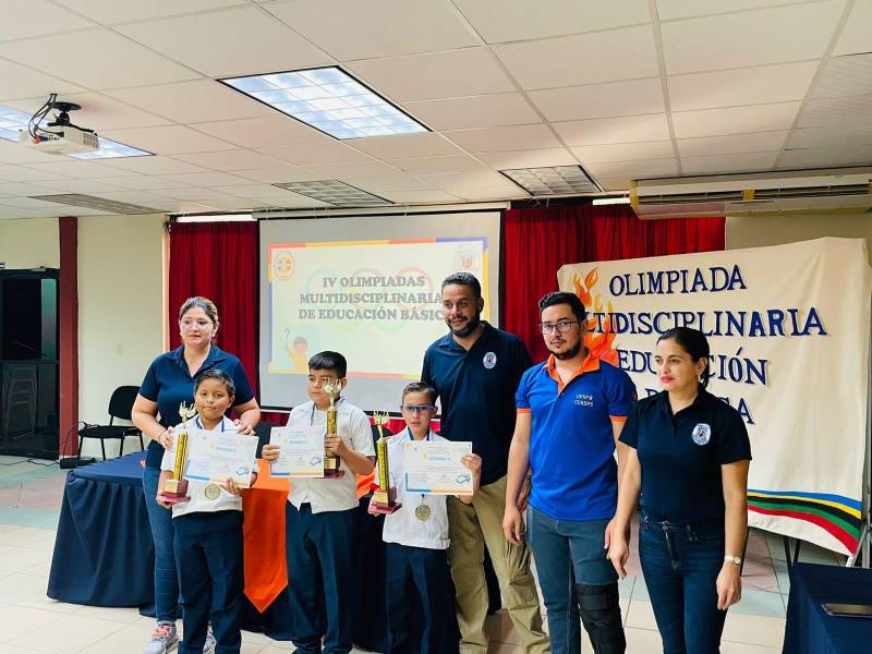 Los alumnos de la escuela Hogar San José, Ángel Fernández, Kennet Lenin Villanueva y Anthony Martínez reciben el trofeo de primer lugar de las Olimpiadas Multidisciplinarias.