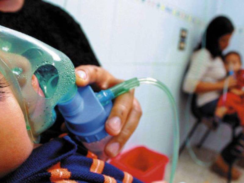 Una madre sostiene la mascarilla de oxigeno de su hijo en un hospital público de Honduras.