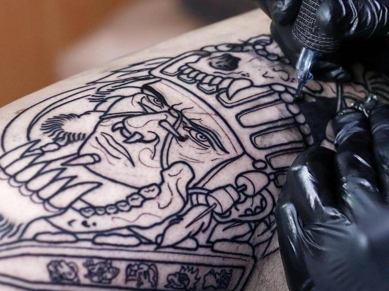 Una persona se tatúa un dibujo con tinta negra en una pierna.