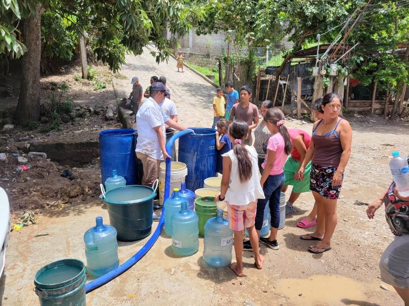 Pobladores de Copán Ruinas llenan baldes y botellones con agua entregada en carros cisterna para abastecer sus hogares.