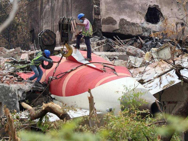 Trabajadores indios retiran los restos del avión de Air India con una grúa del lugar del accidente.