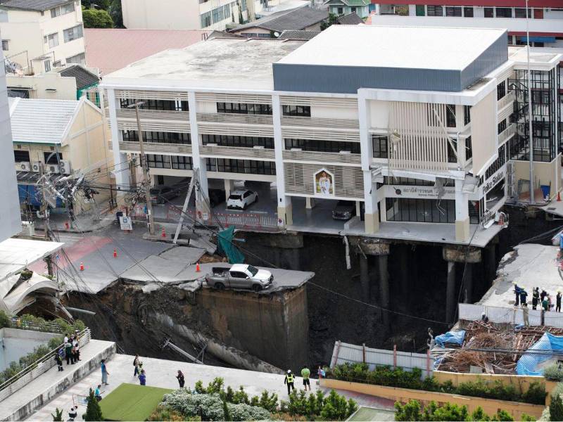 Oficiales tailandeses inspeccionan un enorme socavón tras el colapso de una calle en Bangkok.