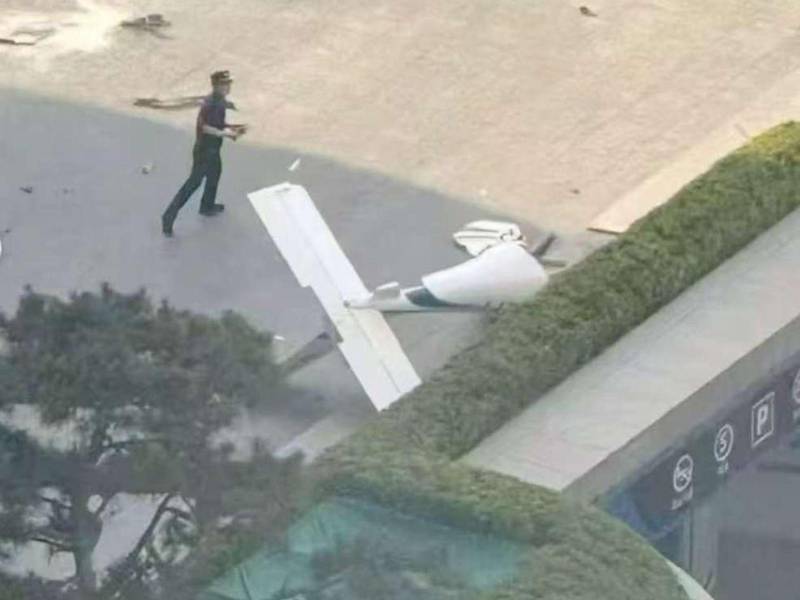 Fotografía cedida que muestra un integrante de la Policía de China frente a un fragmento de una aeronave en una vía próxima al edificio China Zun este viernes, en Pekin (China).