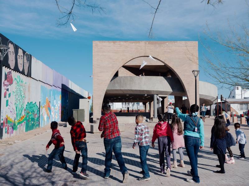 Niños juegan en el nuevo parque público de la biblioteca de Agua Prieta, junto al muro fronterizo lleno de murales.