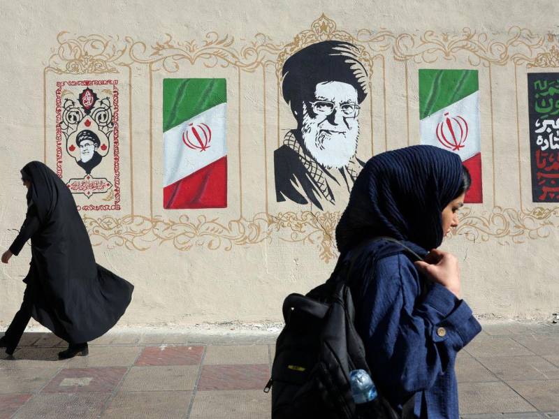 Mujeres iraníes caminan junto a un mural del difunto Líder Supremo iraní, el ayatolá Ali Jamenei, en una calle de Teherán, Irán.