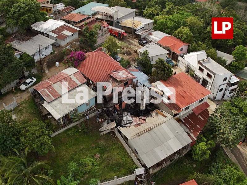 Cuerpos de socorro trabajan entre los escombros tras el incendio que consumió tres viviendas en la colonia Primavera de San Pedro Sula.