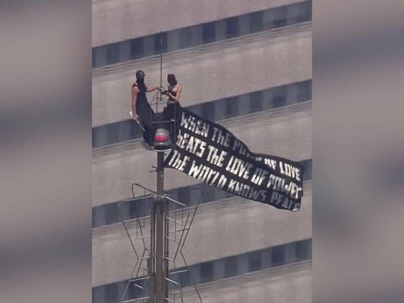 Fotografía tomada de la cuenta oficial de Instagram de Angela Nikolau @Angela_nikolau que muestra a dos personas que subieron sin permiso a la antena de la cima del Empire State Building y ondearon una pancarta con un lema a favor del amor.