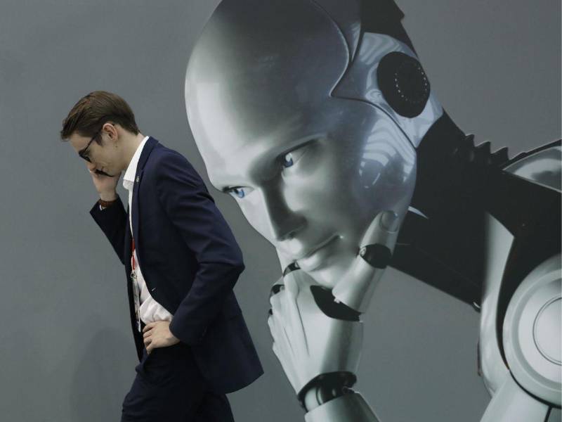 Fotografía de archivo que muestra a una persona hablando por un teléfono móvil mientras pasa por un stand de inteligencia artificial en Barcelona, España.