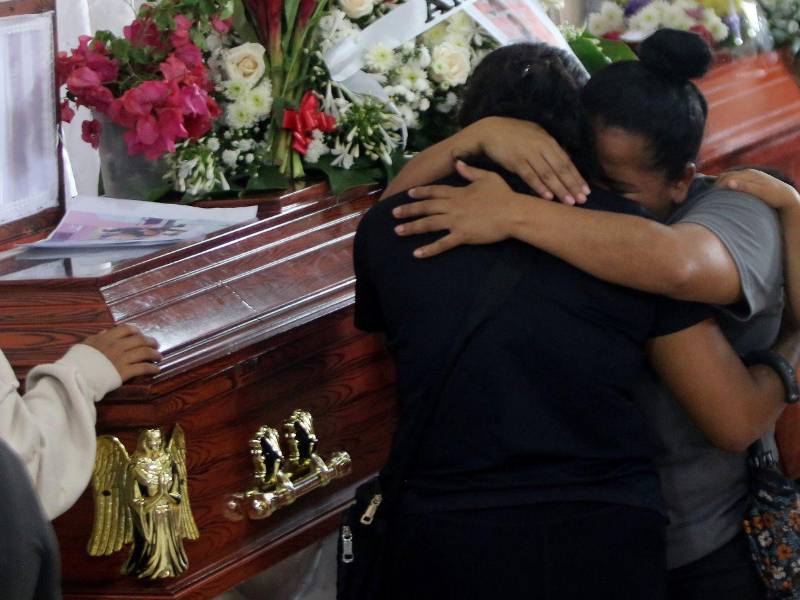 Familiares de Denia Ramírez y de Evelyn Irías se funden en un fuerte abrazo, junto a sus féretros.