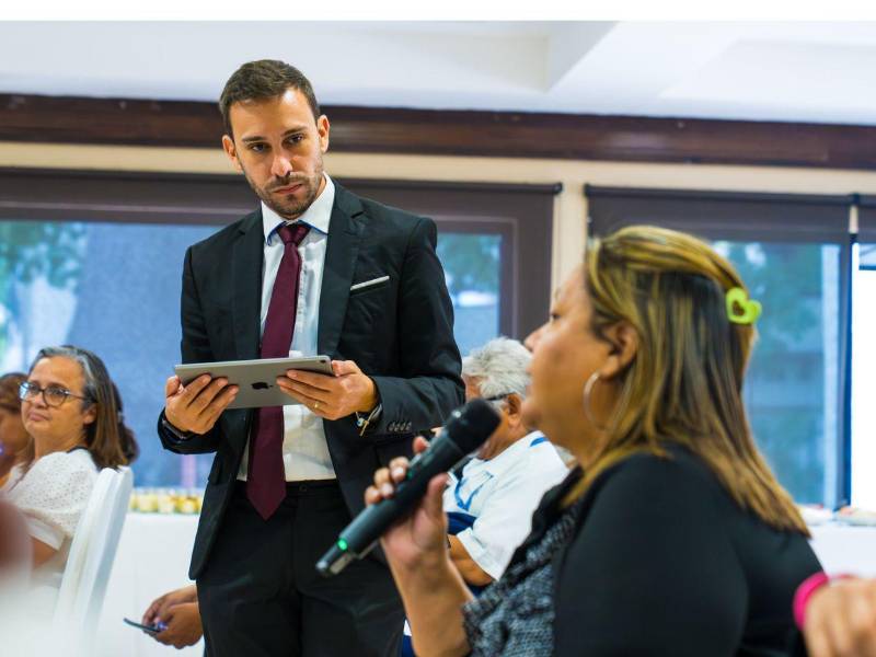 Ismael Cruceta, miembro de unidad de soporte a programas de la Organización Internacional para las Migraciones (OIM), escucha a una de las asistentes de la presentación del informe en San Pedro Sula.