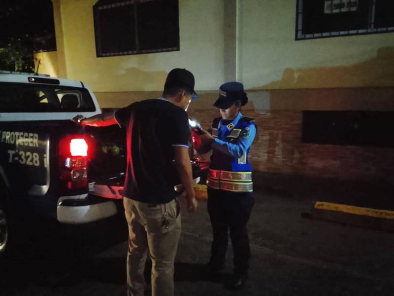 Una agente de la Dirección Nacional de Vialidad y Transporte le realiza una prueba de alcoholemia a un conductor durante un operativo de rutina.