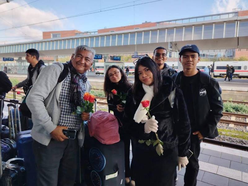 Entregan rosas a estudiantes a su llegada a Alemania.