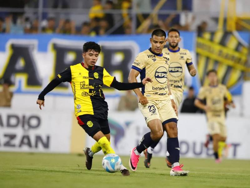 Roberto Osorto conduciendo el balón ante la marca de Alejandro Reyes.