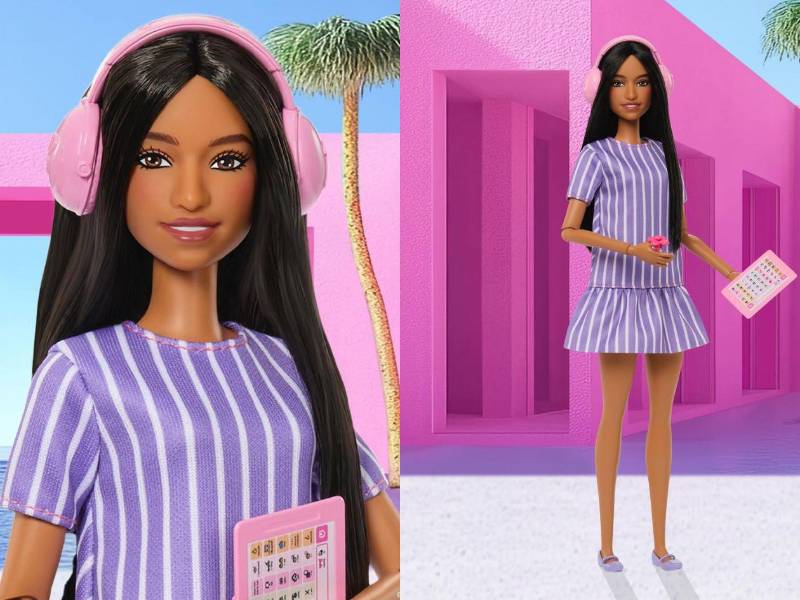 La nueva muñeca viste un vestido de corte A, diseñado para mayor comodidad sensorial, accesorios como un fidget spinner, auriculares con cancelación de ruido y una tableta de comunicación.